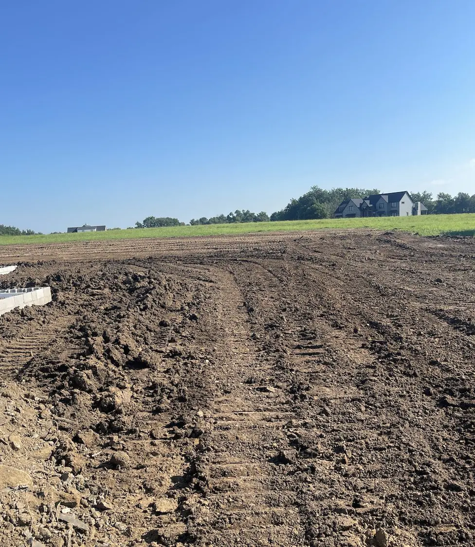 Long stretch of ground graded to bare dirt, with track marks, beside open pasture