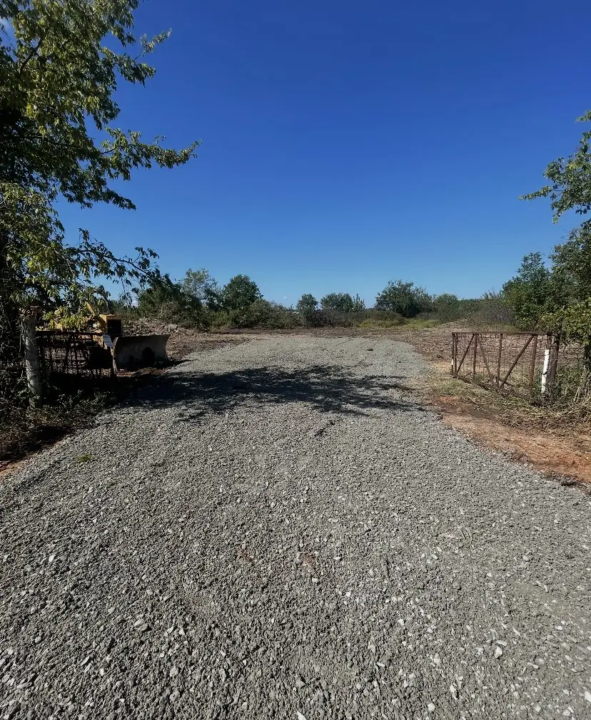 New gravel drive running out between trees to a gate