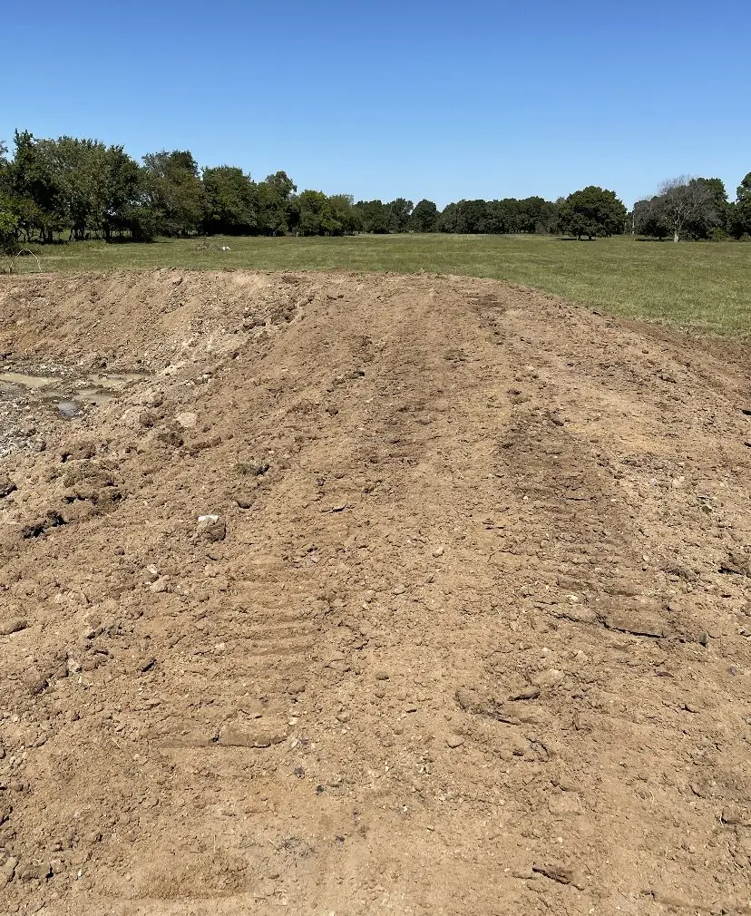 Long strip of bare ground graded smooth through a pasture