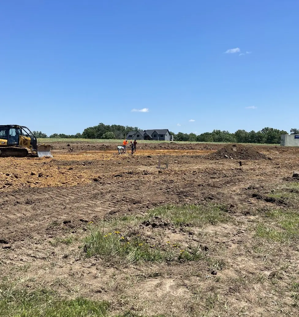 Dozer and crew working a large graded site in open country