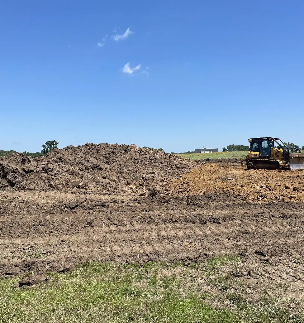 Dozer working beside a dirt pile on a graded site