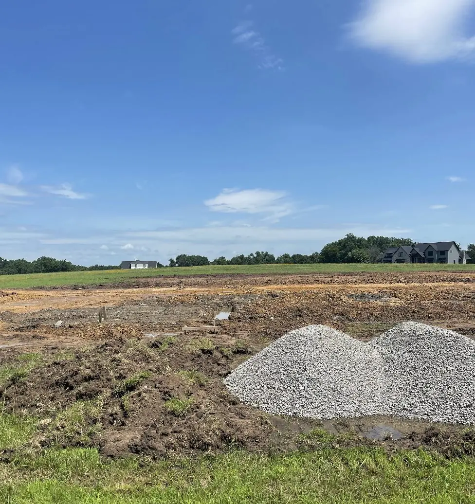 Freshly graded lot with two piles of gravel waiting to be spread